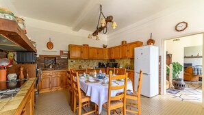 Una cocina con armarios de madera, una mesa de comedor preparada para cuatro personas y una lámpara colgante.