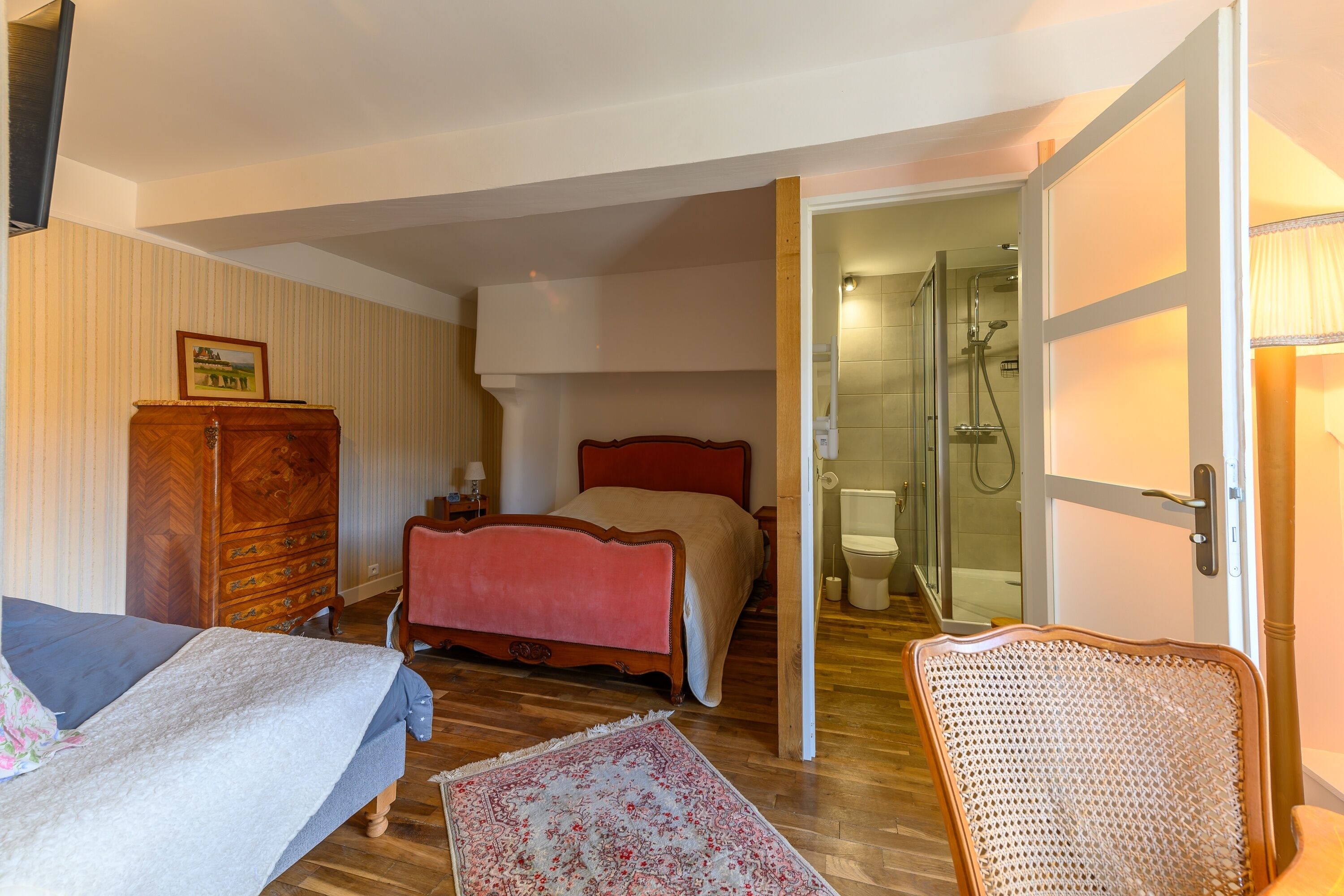 Une chambre à coucher comprenant un lit, une commode, une chaise et une salle de bain avec douche.