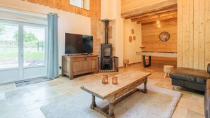 A cozy living room with a fireplace, a television, and a billiard table.