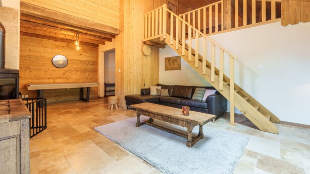 A spacious living area with a wooden staircase, a sofa, and a coffee table.