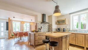 A spacious kitchen with a large island, wooden cabinets, and a modern pendant light.