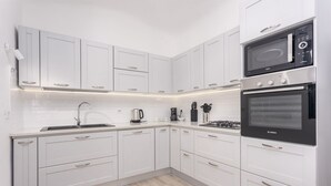 A modern kitchen with white cabinets, a Bosch oven, and a microwave. - Independent Domu Fama (Tertenia)