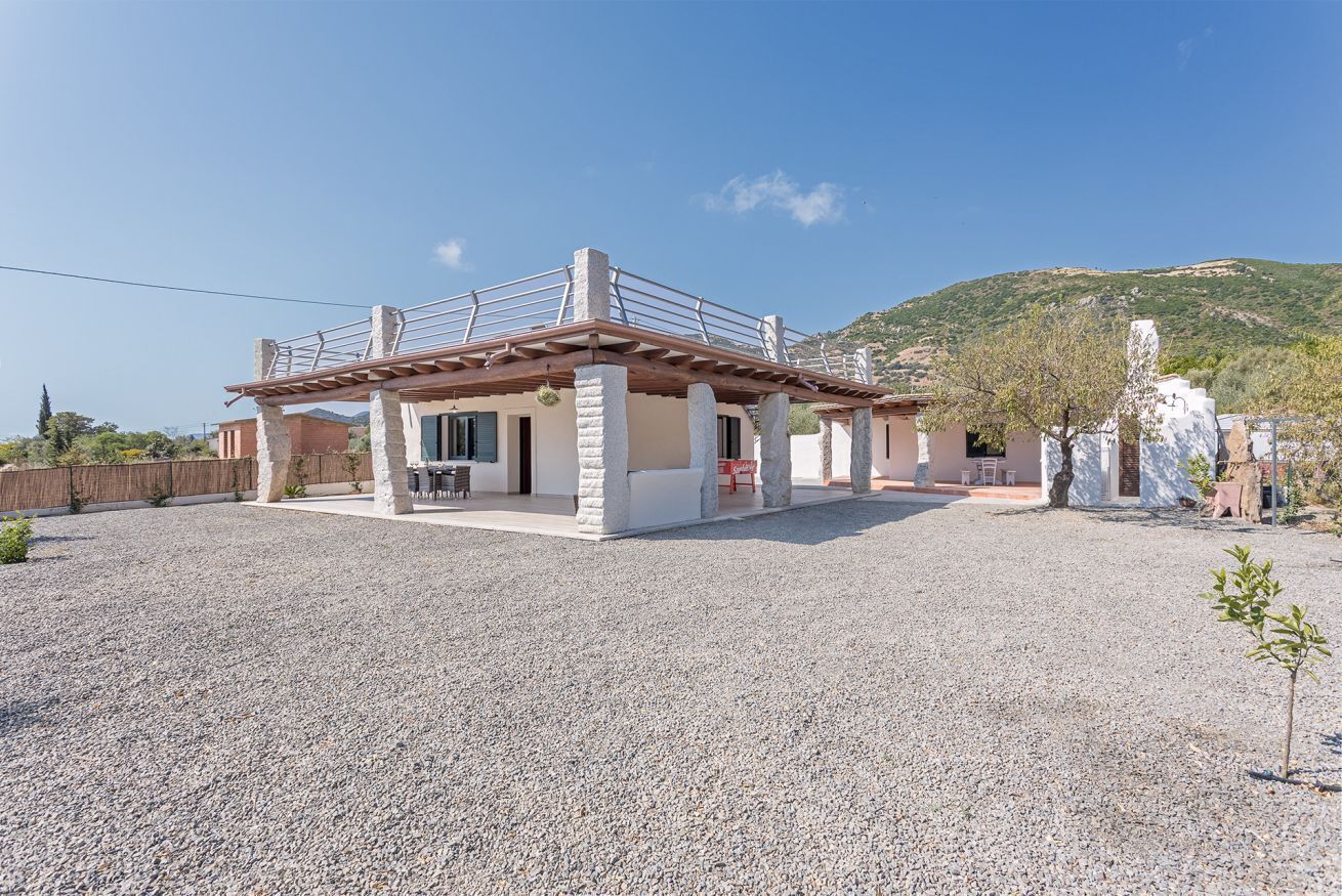 A two-story house with a patio area, a pergola, and a view of a hill.