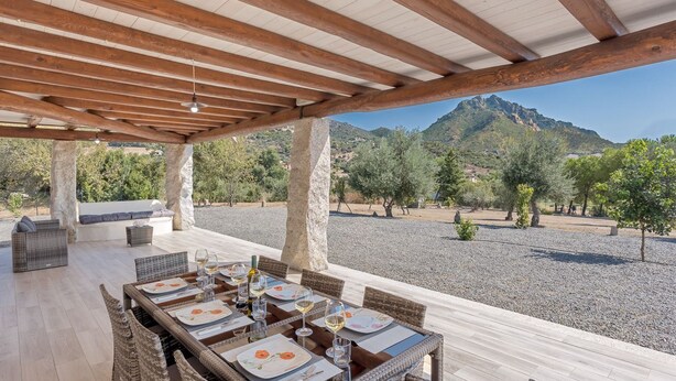 An outdoor dining area with wicker furniture and a view of a mountainous landscape. - Independent Domu Fama (Tertenia)