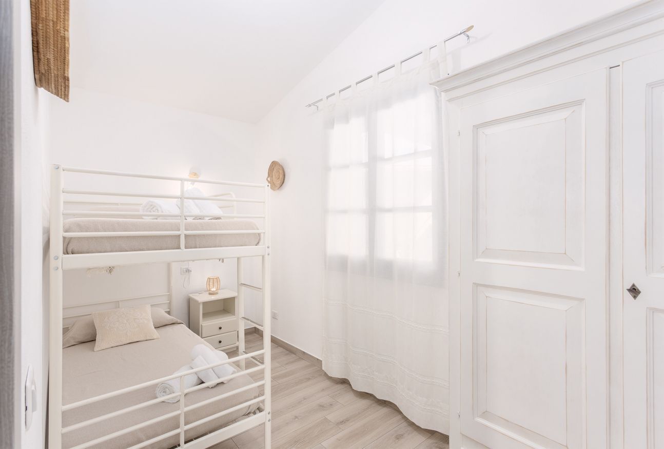 Habitación con literas, una mesita de noche pequeña, una lámpara y una puerta con manija.