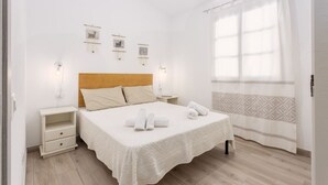 A neatly arranged bedroom with a bed, bedside tables, and a window with curtains. - Independent Domu Fama (Tertenia)