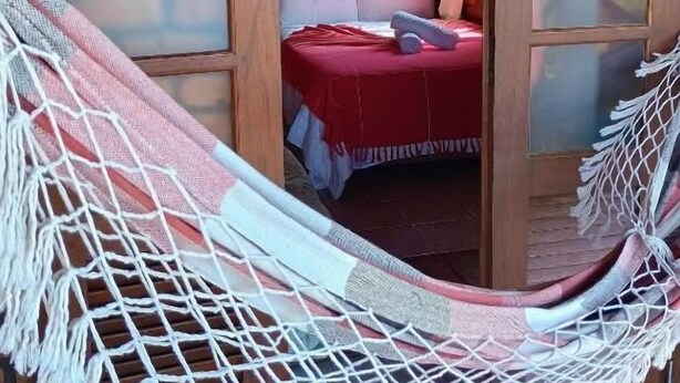 Un hamac dans une pièce où se trouvent un lit, un tableau au mur et un appareil de climatisation.