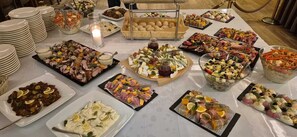 Une table de buffet garnie de divers plats et agrémentée d’un centre de table composé de bougies.