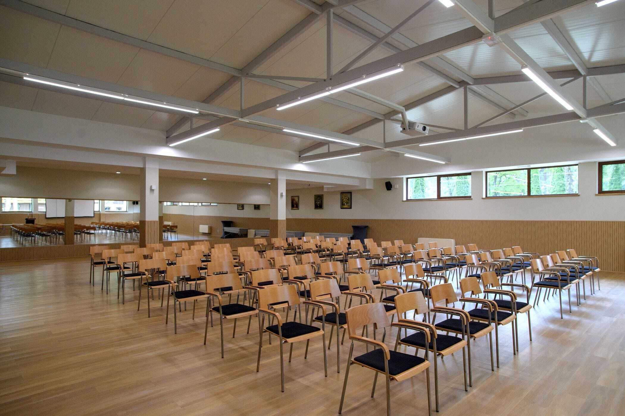 A spacious hall with rows of chairs and a high ceiling with exposed beams.