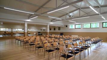 A spacious hall with rows of chairs and a high ceiling with exposed beams.