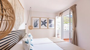 A hotel room with a bed, a macrame wall hanging, and framed artwork on the wall. - SES VELES IBIZA HOUSE (Santa Eulalia del Rio)