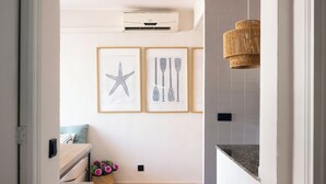 A modern kitchen with a wooden countertop, a hanging wicker light fixture, and framed artwork on the wall. - SES VELES IBIZA HOUSE (Santa Eulalia del Rio)