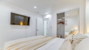Un dormitorio moderno con una cama grande, un armario y un televisor montado en la pared.