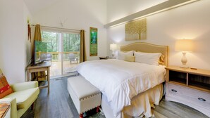 Ein Schlafzimmer mit einem großen Bett, einem Schreibtisch und einem Stuhl. Ein Fenster bietet Blick auf Bäume.