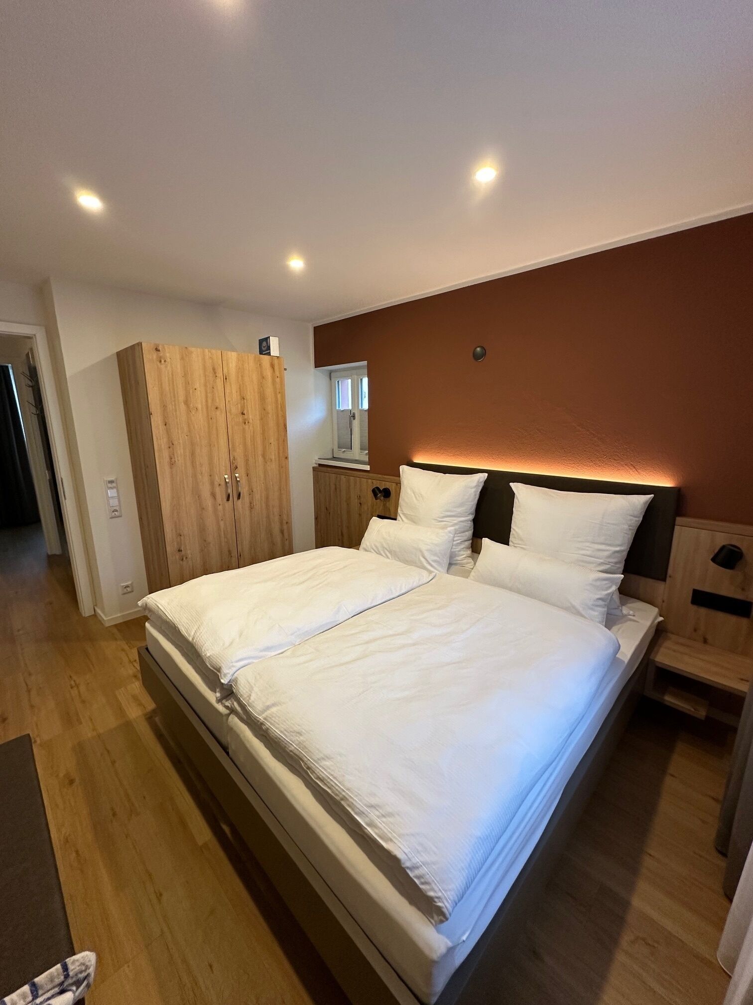 A bedroom with a large bed, wooden wardrobe, and a mirror above the bed.