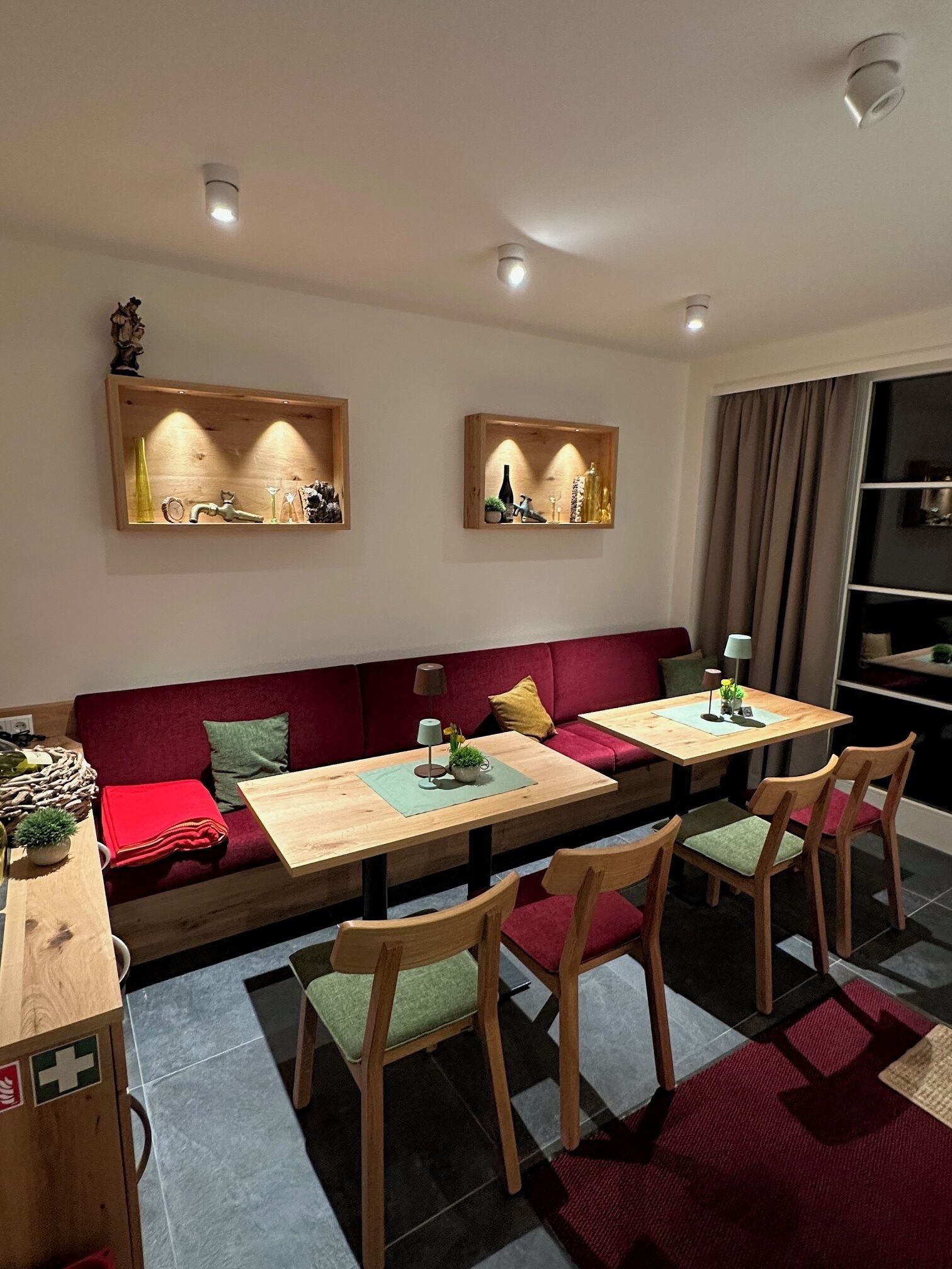 A modern living room with a sofa, a dining table, and chairs. There are two wall-mounted shelves with decorative items.