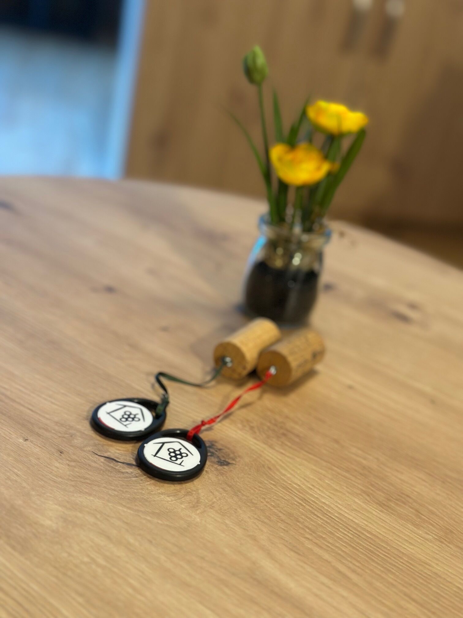 A wooden table with a vase of yellow flowers and two cylindrical objects with wires.
