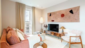 Un salon moderne avec un canapé, une table basse, un téléviseur et une lampe.
