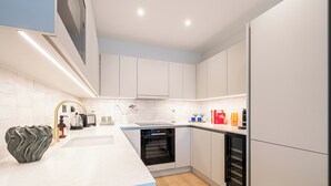 A modern kitchen with white cabinetry, a built-in oven, and a refrigerator. - Light and Space Retreat (London)