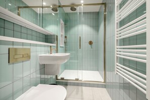 Une salle de bain moderne avec une douche à parois de verre, un lavabo blanc et des toilettes.