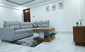 Un salon moderne avec un canapé d’angle gris, une table basse en bois et un tapis noir et blanc.