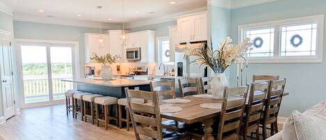 A spacious kitchen with a central island, wooden chairs, and a dining table set for six.