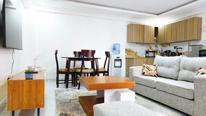 Un salon moderne avec une table basse en bois, un canapé gris et un coin repas comprenant une table et des chaises en bois.