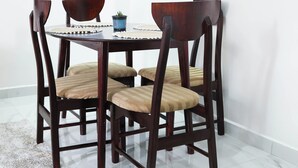 Une table à manger avec quatre chaises, une petite plante en pot et un bord décoratif.