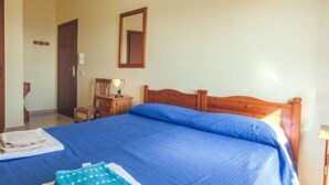 Quarto com cama de madeira, mesa de cabeceira, cadeira, espelho e porta.