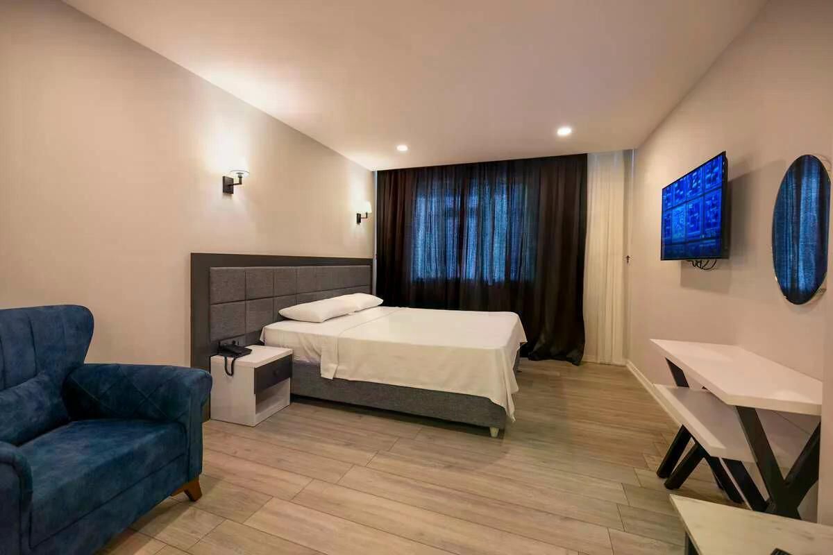 Ein modernes Hotelzimmer mit Bett, Schreibtisch, Stuhl und Fernseher.