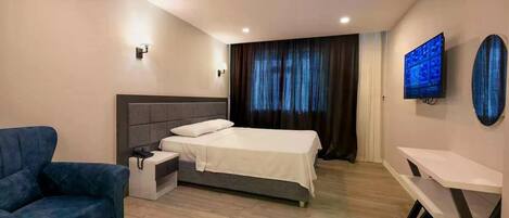 Ein modernes Hotelzimmer mit Bett, Schreibtisch, Stuhl und Fernseher.