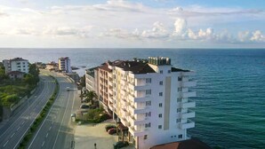 A multi-story hotel with balconies, located near a coastal road with a view of the sea. - Venesia Hotel (Arsin)