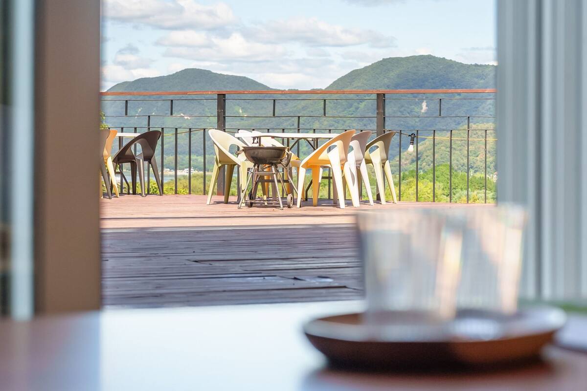 Una terraza con mobiliario exterior y una parrilla, con vistas a un paisaje montañoso.