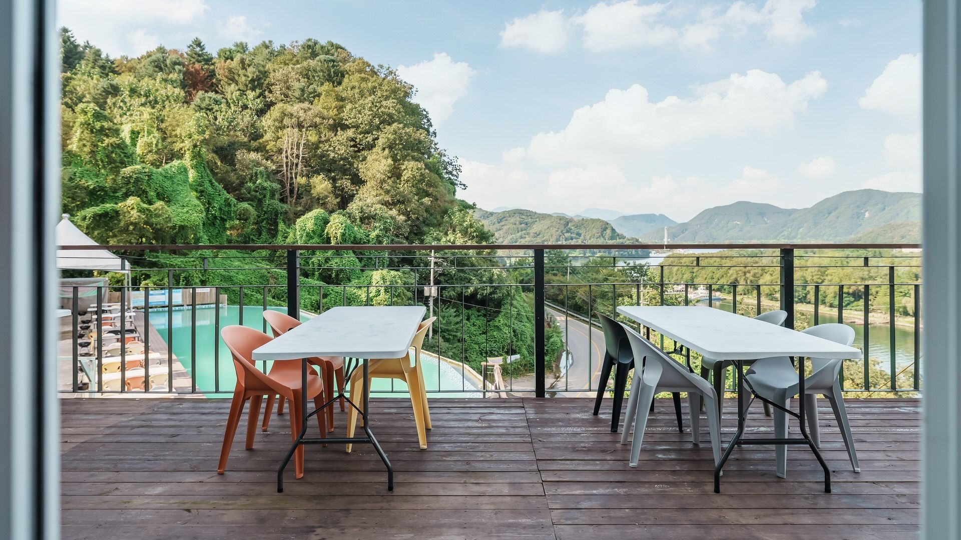 Une terrasse en bois avec des sièges extérieurs, offrant une vue sur un paysage verdoyant et luxuriant ainsi que sur une étendue d’eau.