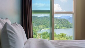 Une chambre d’hôtel avec un lit, une fenêtre et une vue sur un lac et des montagnes.