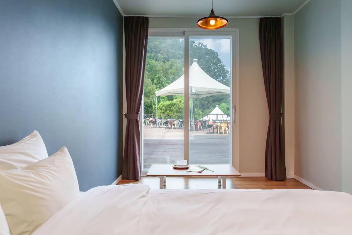 Un dormitorio con una cama grande, una ventana con cortinas y vistas a un evento al aire libre.