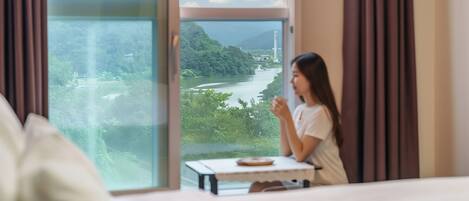 A room with a large window overlooking a river and greenery.
