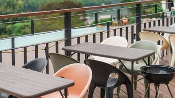 An outdoor seating area with tables and chairs, overlooking a body of water.