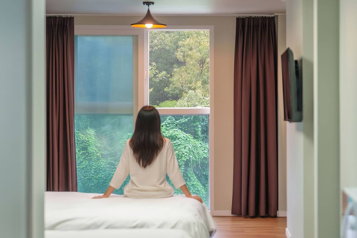 Una habitación con cama, ventana con cortinas y una lámpara colgante.