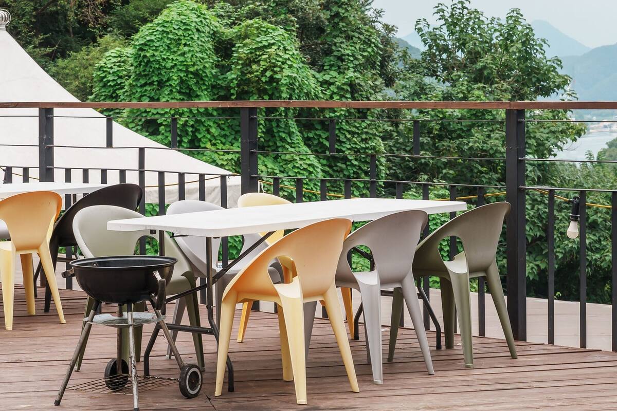Terraza con mobiliario exterior y una parrilla, con vista panorámica a montañas y vegetación.