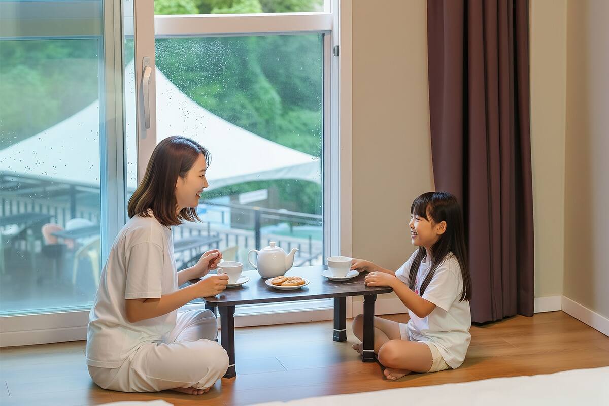 Una habitación con un ventanal grande, una mesa con juego de té y vistas a la vegetación.
