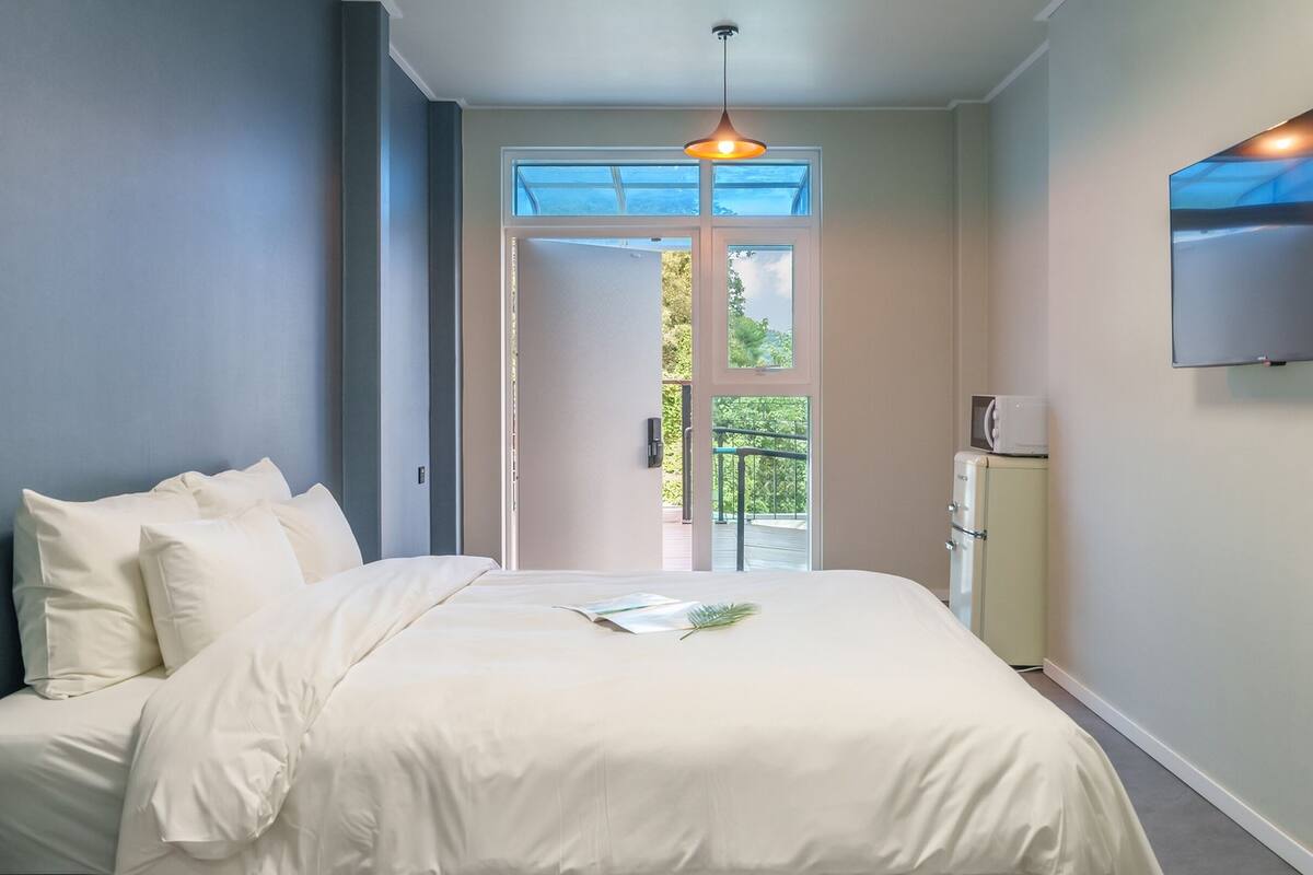 Un dormitorio con cama, televisión y vista al exterior.