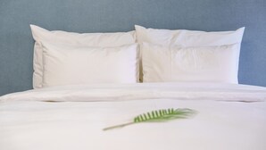 Ein Bett mit weißer Bettwäsche und zwei Kissen vor einer blauen Wand.