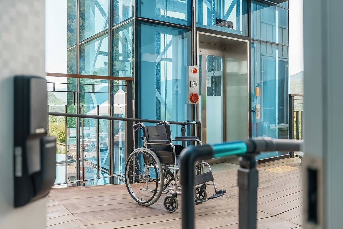 Una silla de ruedas en un edificio moderno con grandes ventanales y una terraza de madera.
