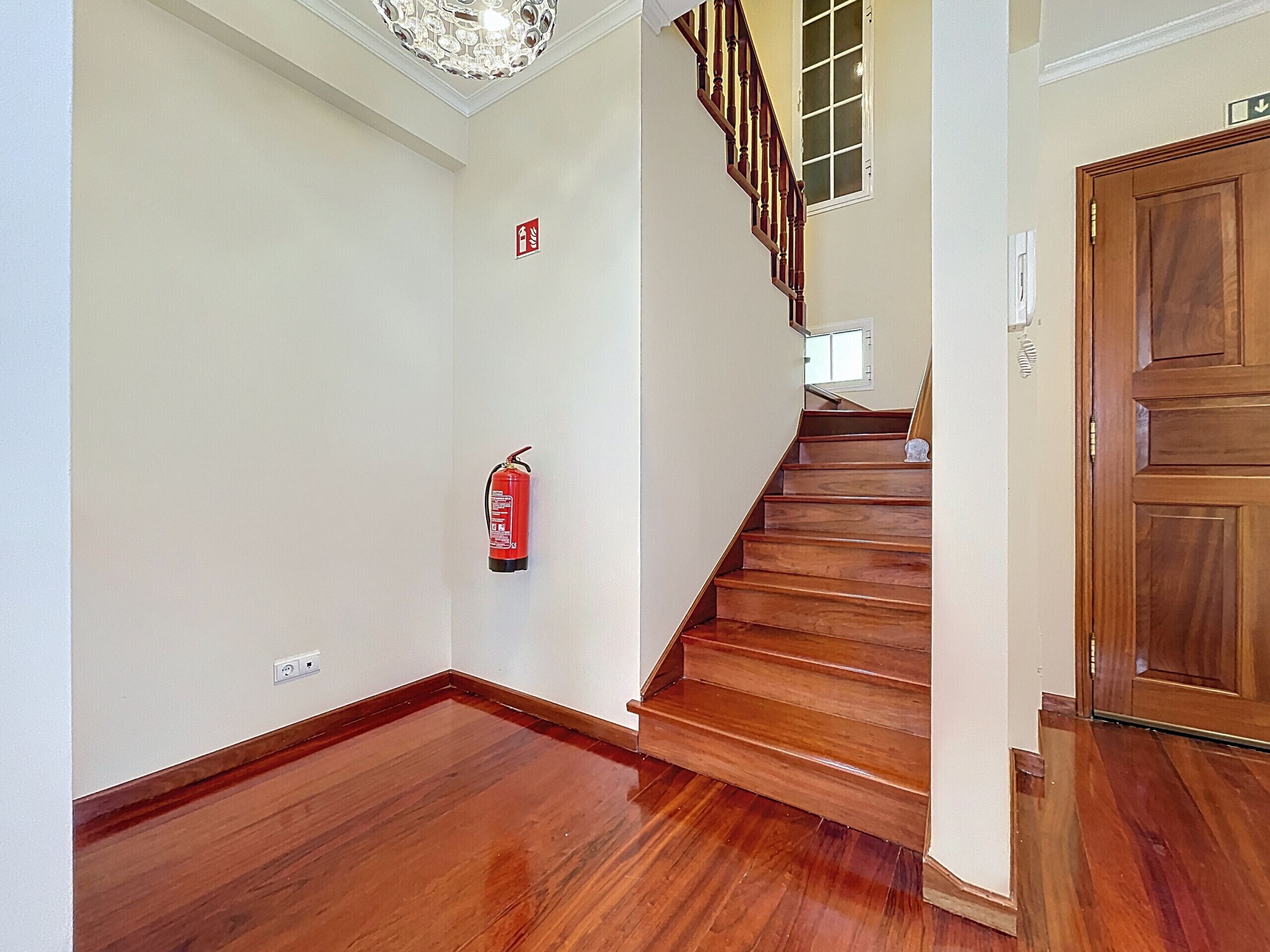 Un escalier en bois avec un extincteur fixé au mur.