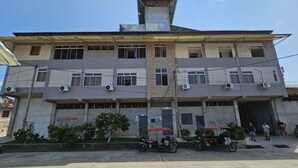 Un edificio a più piani con una scalinata centrale, condizionatori d'aria e un ingresso chiuso da cancello.