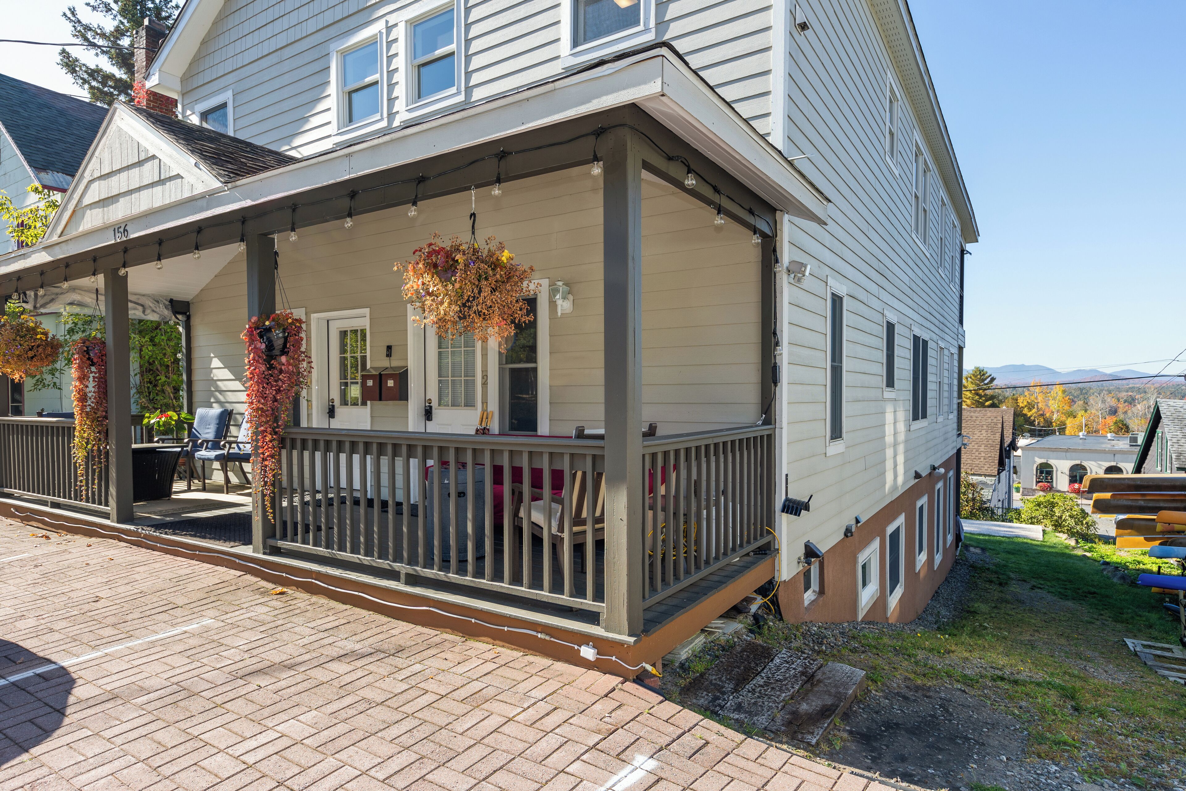 A two-story house with a covered porch, a brick pathway, and a grassy yard.