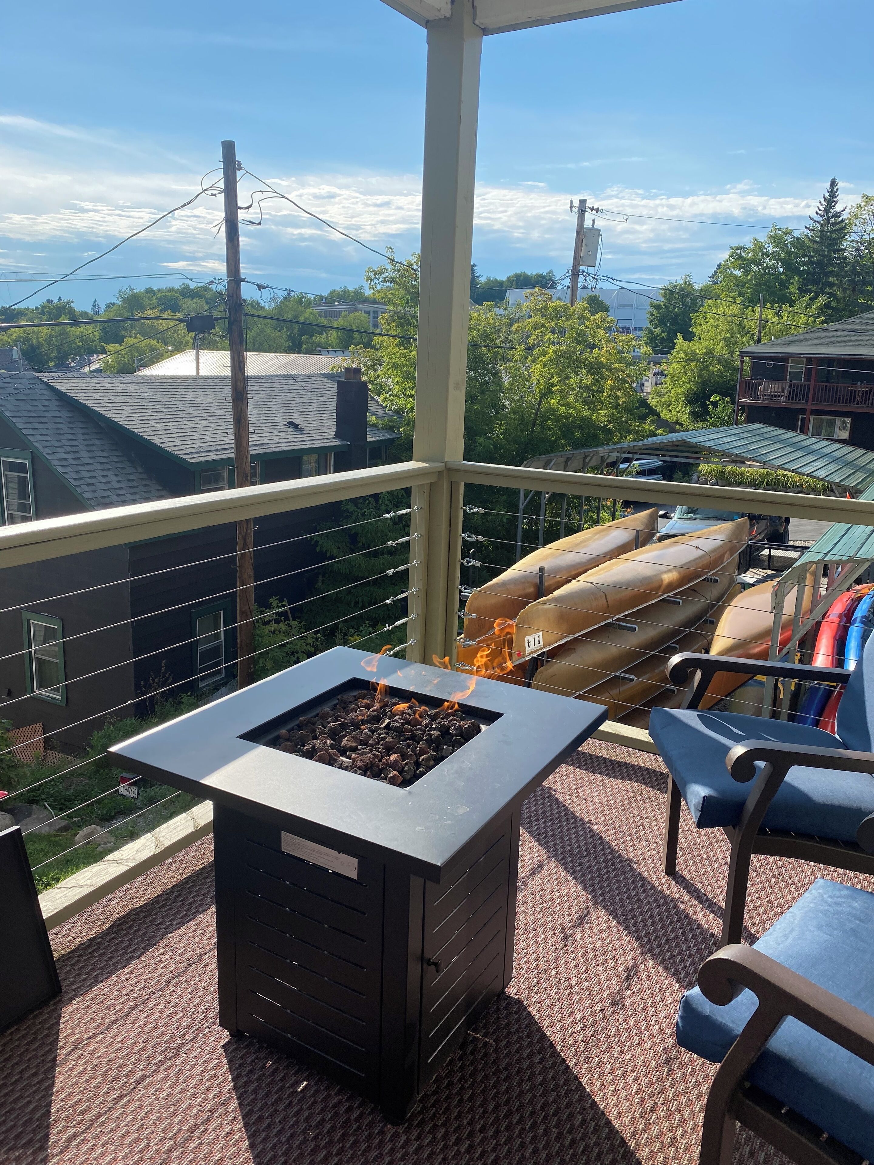 A balcony with a built-in fire pit, outdoor seating, and a view of the neighborhood.