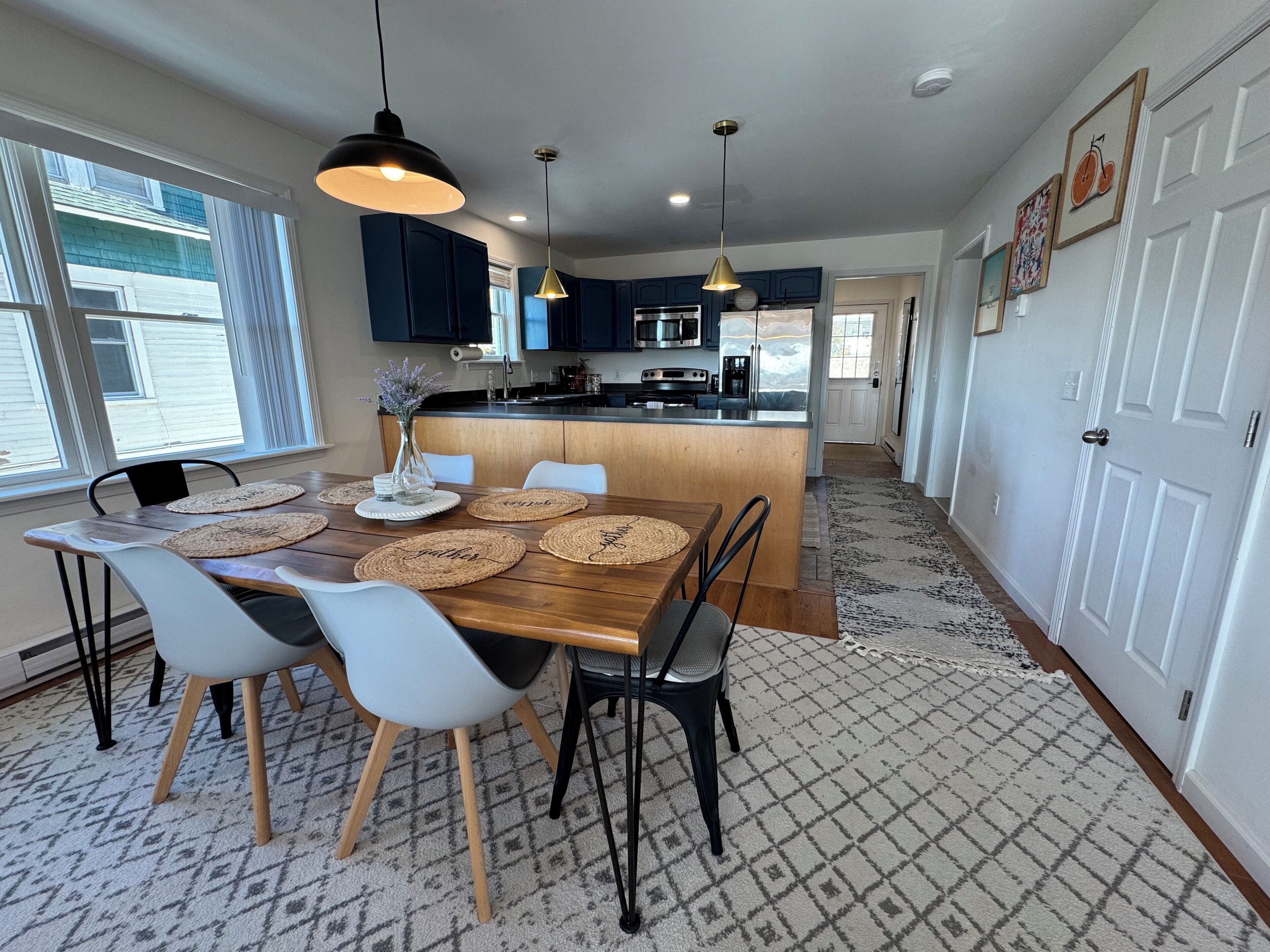 A modern kitchen with dark blue cabinets, a central island, and pendant lighting.