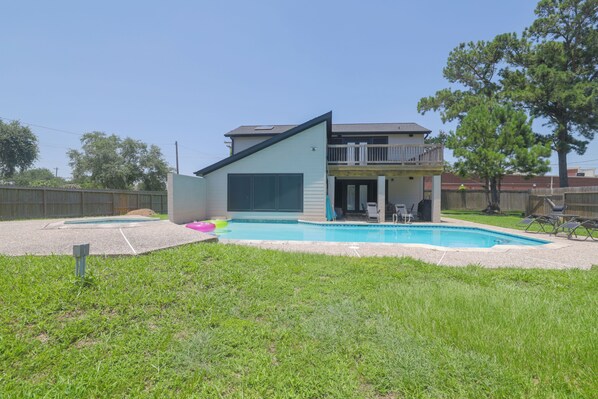 A modern two-story house with a swimming pool, a covered patio, and a fenced backyard.